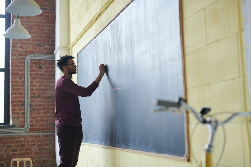 man writing on a blackboard